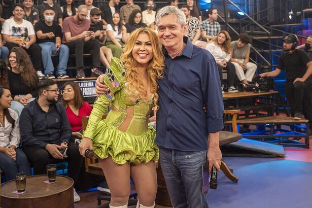 Joelma de look verde, sorrindo, ao lado de Serginho Groisman durante gravação do Altas Horas, da TV Globo