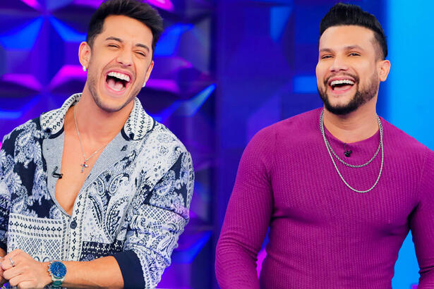 Kevin de camisa social estampada em branco e preto, sorrindo; Israel Novaes de camisa manga longa roxa, colar de prata, sorrindo durante gravação do Programa Silvio Santos, do SBT