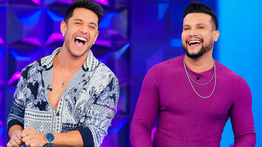 Kevin de camisa social estampada em branco e preto, sorrindo; Israel Novaes de camisa manga longa roxa, colar de prata, sorrindo durante gravação do Programa Silvio Santos, do SBT