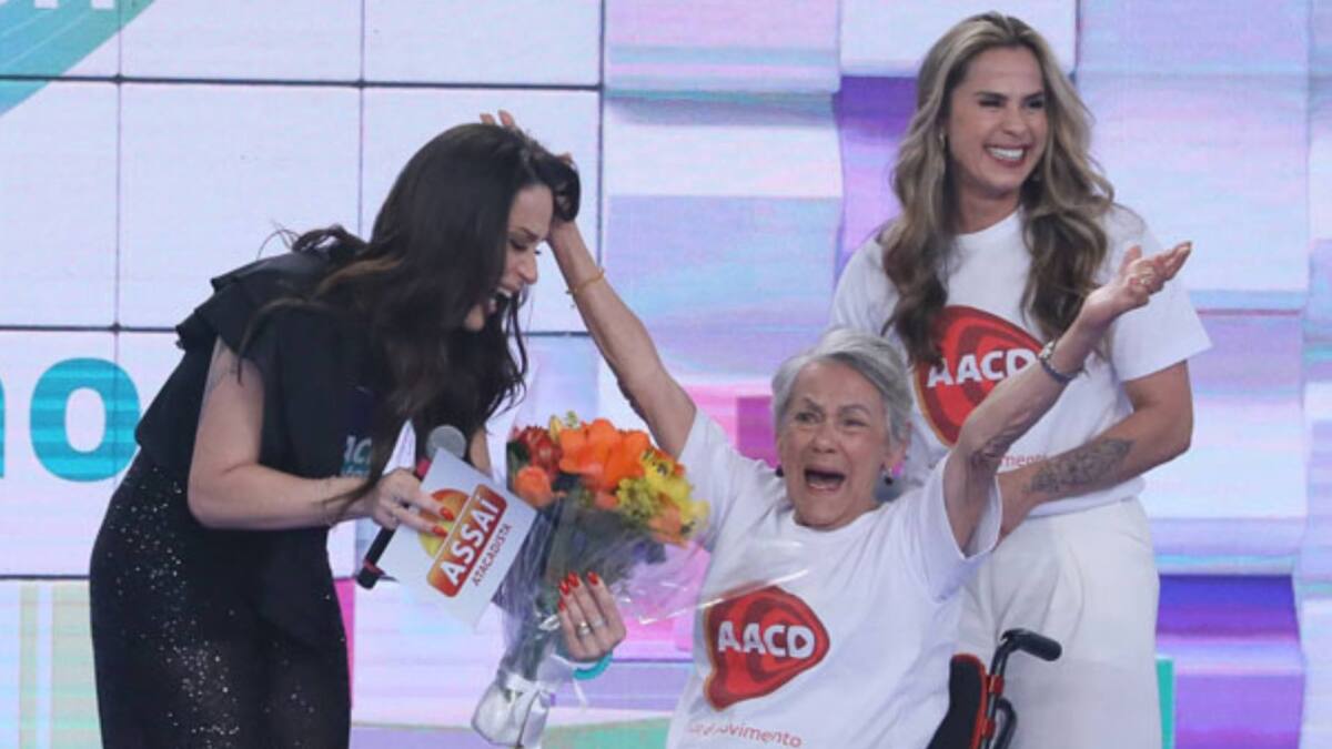 Nadja Haddad ao lado da mãe (na cadeira de rodas) e da irmã no palco do teleton 2022