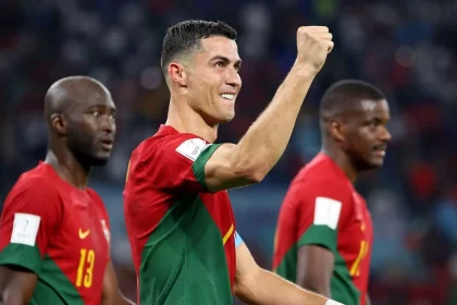 Cristiano Ronaldo, olhando pela lateral, com o braço direito levantando, ao comemorar um gol com a camisa de Portugal