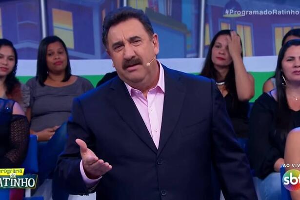 Ratinho de palito preto, camisa social rosa claro discursando em seu programa no SBT