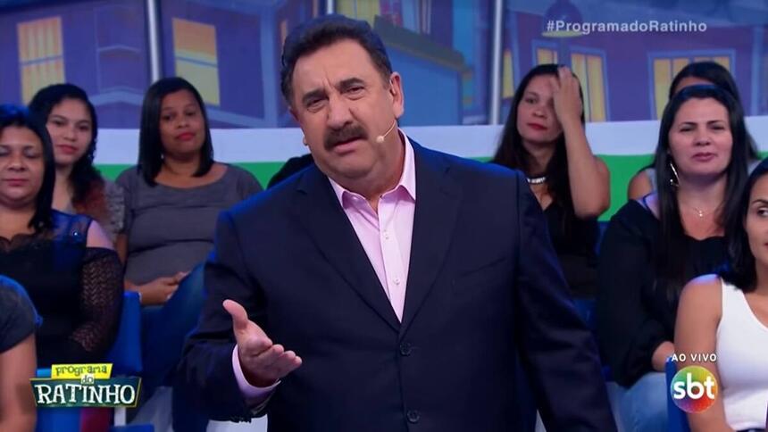 Ratinho de palito preto, camisa social rosa claro discursando em seu programa no SBT