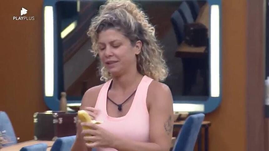 Bárbara segurando uma banana em pé na área interna da sede