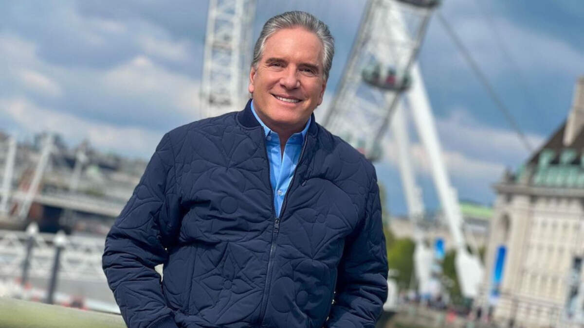 Roberto Justus em foto posada com um casaco azul e mãos no bolso