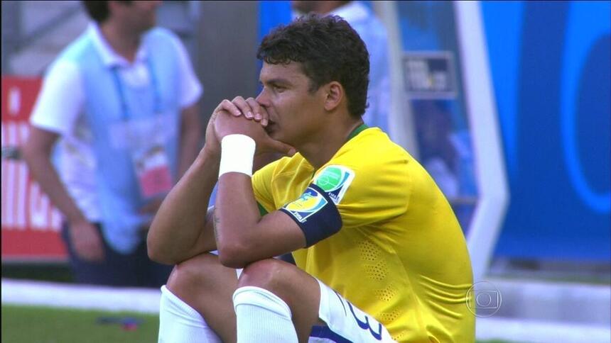 Thiago Silva, com a camisa do Brasil, sentado, chorando, com as mãos apoiadas no queixo