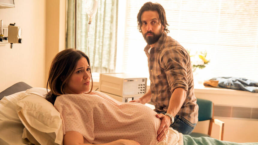 Trecho de um episódio da série This Is Us. Mulher grávida está na cama de um hospital, deitada, com o marido colocando a mão sobre a sua barriga