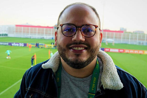 Victor Pereira cobrindo um treino da Seleção Brasileira, ao fundo no gramado