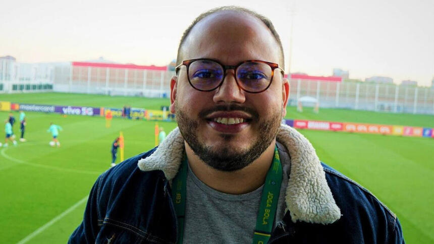 Victor Pereira cobrindo um treino da Seleção Brasileira, ao fundo no gramado