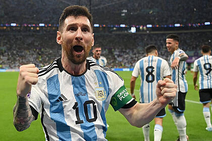 Messi com os braços abertos e punhos fechados, comemorando gol com a camisa da Argentina