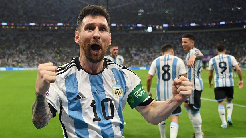 Messi com os braços abertos e punhos fechados, comemorando gol com a camisa da Argentina