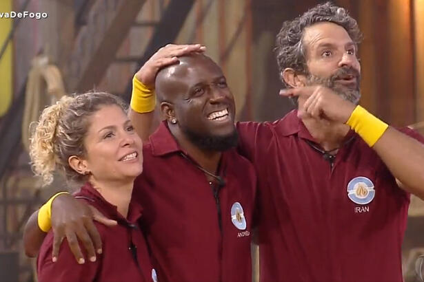 André Marinho sorrindo ao lado de Bárbara Borges e Iran Malfitano, ambos usando a farda da Prova de Fogo de A Fazenda 14, da Record TV