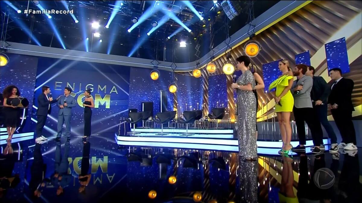 Elenco no palco do especial Família Record participando de brincadeira de enigma em uma interação com a plateia. 