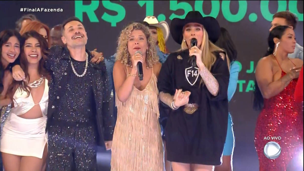 Bárbara Borges de mãos dadas com Adriane Galisteu, com outros participantes ao fundo, em trecho da final de A Fazenda 14