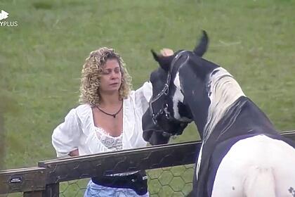 Bárbara Borges vestida com uma blusa branca e short jeans de frente para o cavalo Colorado.