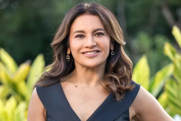 Dira Paes com camisa decotada preta, cabelo solto em corte camada, sorrindo, durante gravação de novela