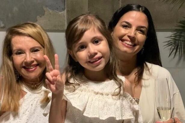 Emanuelle Araujo, sofia e avó de camisa branca, sorrindo, durante reveillon