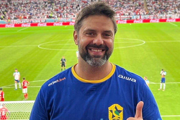 Fábio Rabin em foto posada em um jogo do Brasil na Copa, com o estádio do fundo