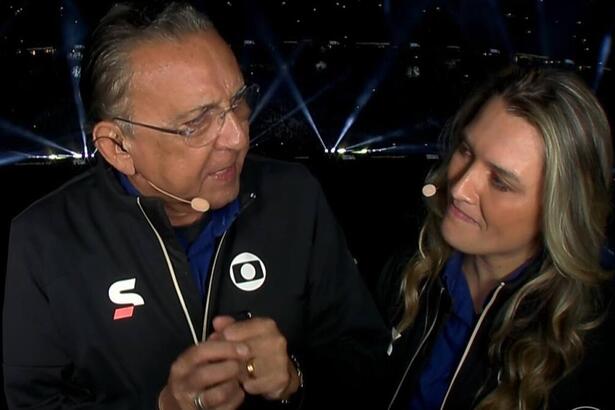 Galvão Bueno ao lado de Ana Thaís Matos, vestidos do uniforme de esporte da TV Globo, na cabine do estádio