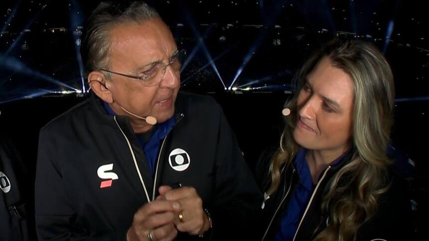 Galvão Bueno ao lado de Ana Thaís Matos, vestidos do uniforme de esporte da TV Globo, na cabine do estádio