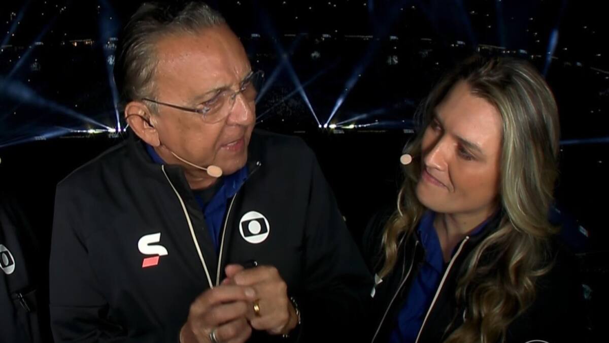 Galvão Bueno ao lado de Ana Thaís Matos, vestidos do uniforme de esporte da TV Globo, na cabine do estádio