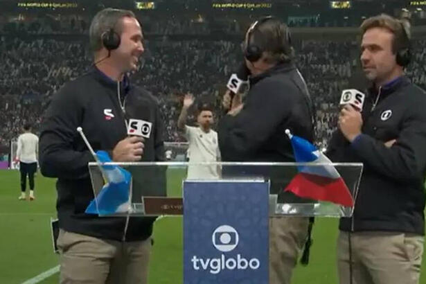 Galvão Bueno, ao lado de Caio Ribeiro e Roger Flores, na beira do gramado, tentando se comunicar com Messi ao fundo, em trecho de transmissão da TV Globo