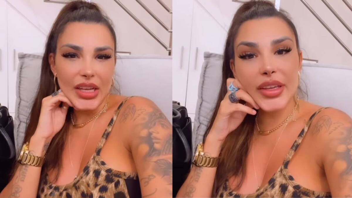 Jenny Miranda vestida com uma blusa estampada, com a mão no queixo.