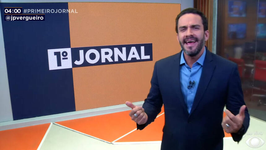 João Paulo Vergueiro, de terno e roupa social escura, no estúdio do 1º Jornal