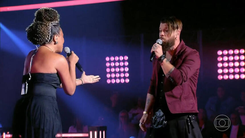 Júlio Mallaguthi e Val Andrade em trecho da batalha no palco do The Voice Brasil 11