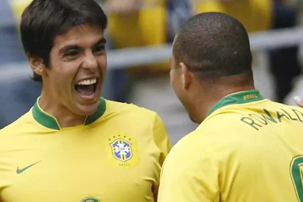 Kaká usando o uniforme da Seleção Brasileira, com a boca aberta, ao lado de Ronaldo Fenômeno, careca, de costa, durante jogo da Copa do Mundo