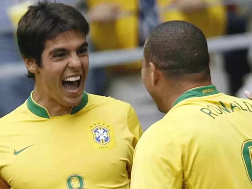 Kaká usando o uniforme da Seleção Brasileira, com a boca aberta, ao lado de Ronaldo Fenômeno, careca, de costa, durante jogo da Copa do Mundo