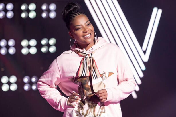 Ludmilla, com uma roupa rosa e um sorriso no rosto, no palco do The Voice+