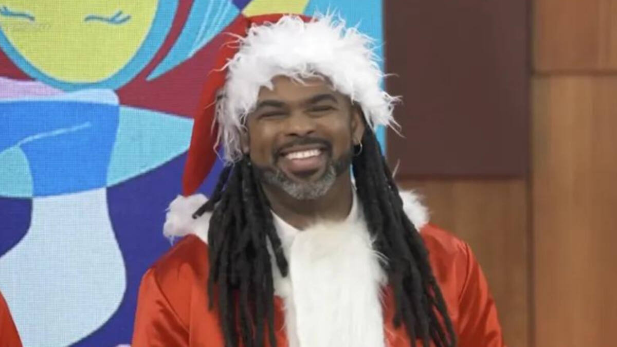Manoel Sores sorrindo, vestido de Papai Noel no estúdio do Encontro