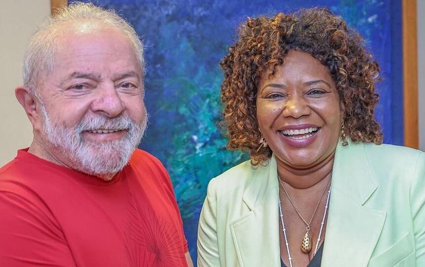 Lula com camisa básica vermelha, sorrindo, ao lado de Margareth Menezes, de blazer verde, sorrindo durante reunião em Brasília