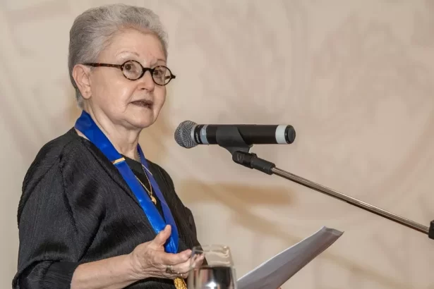 Maria Adelaide Amaral, com um medalha com um cordão azul no peito, discurso co