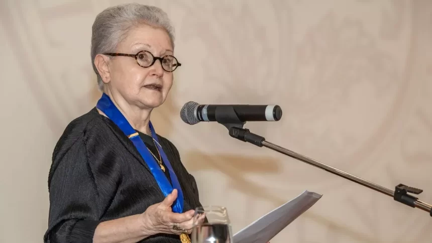 Maria Adelaide Amaral, com um medalha com um cordão azul no peito, discurso co