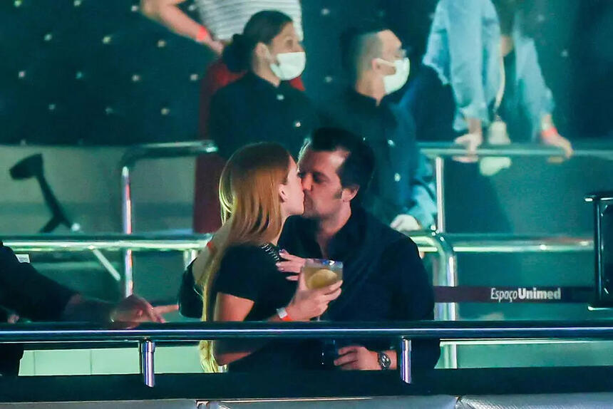 Marina Ruy Barbosa de camisa preta, de perfil beijando Guilherme Mussi durante show de Marisa Mussi