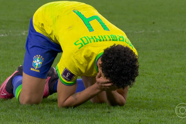 Zagueiro Marquinhos agachado, com a mão no rosto, com a camisa da Seleção Brasileira na Copa do Mundo