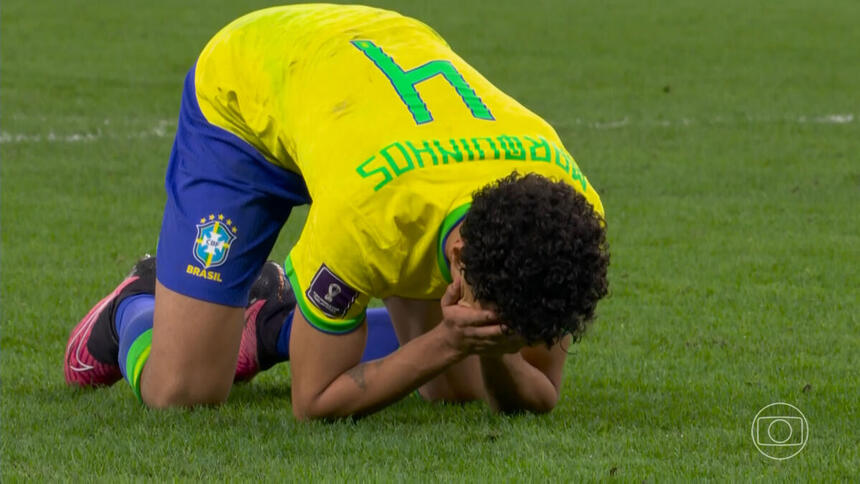 Zagueiro Marquinhos agachado, com a mão no rosto, com a camisa da Seleção Brasileira na Copa do Mundo