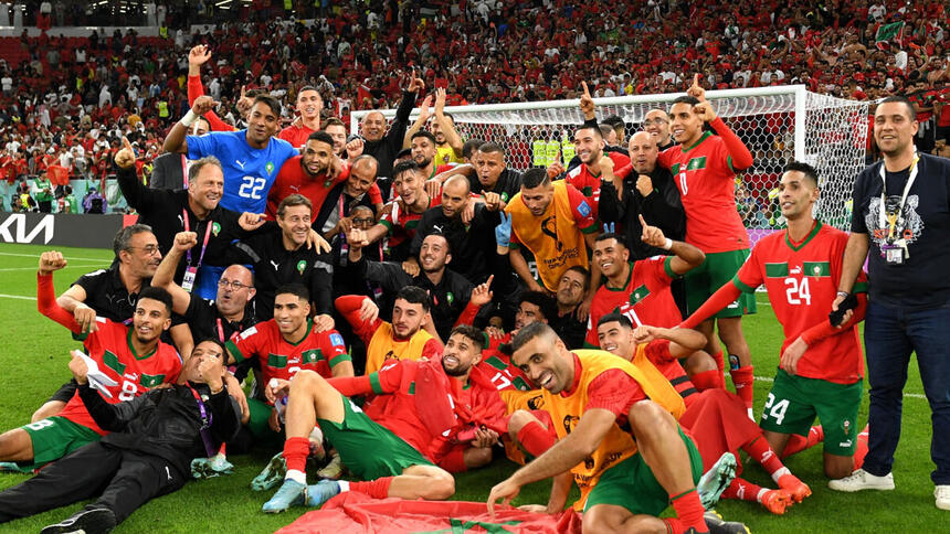 Jogadores e comissão técnica do Marrocos em foto posada juntos no gramado da Copa, após a vitória contra Portugal