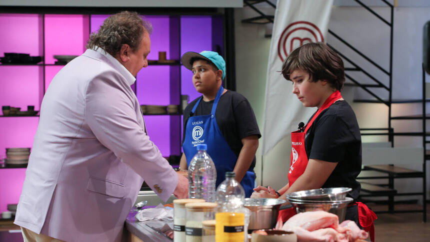 Erick Jacquin de frente para a bancada com dois participantes no MasterChef Júnior