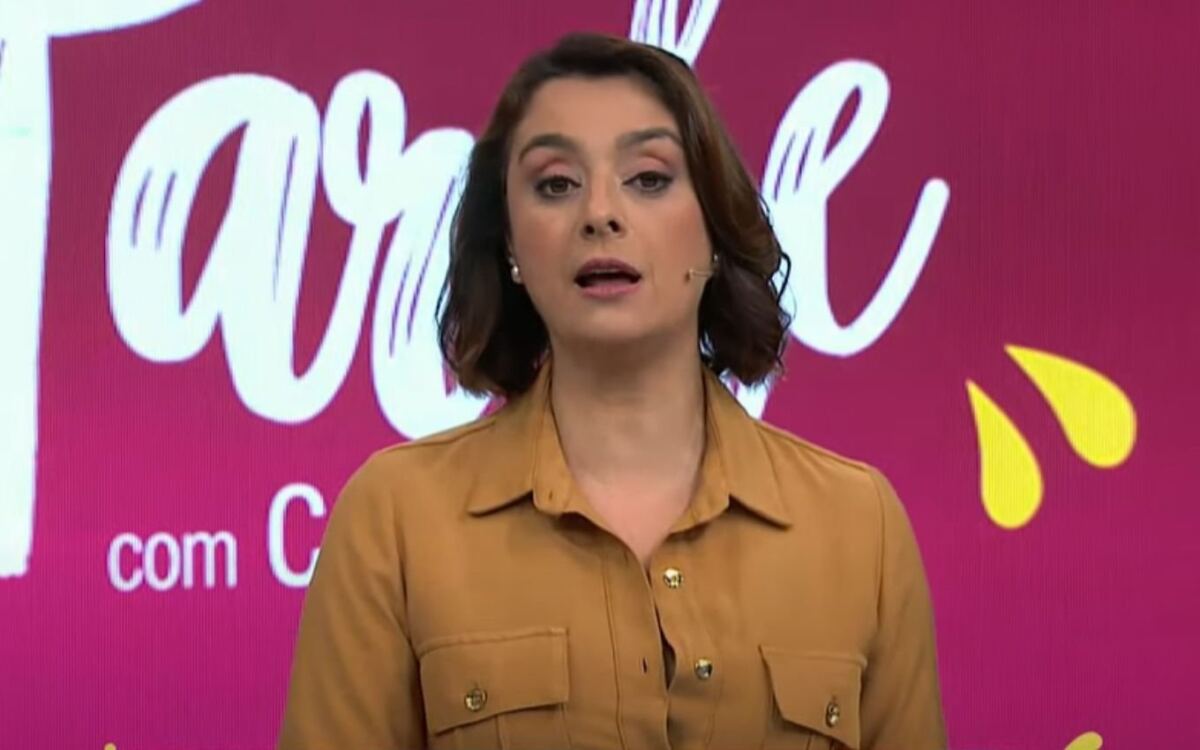 Catia Fonseca com roupa laranja, em frente ao telão, no estúdio do Melhor da Tarde
