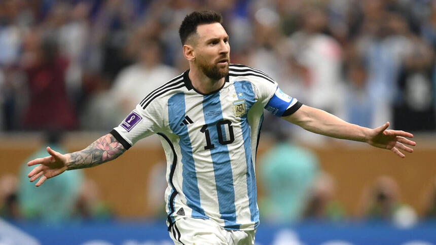 Messi, com os braços abertos, comemorando um gol com a camisa da Argentina na final da Copa do Mundo 2022