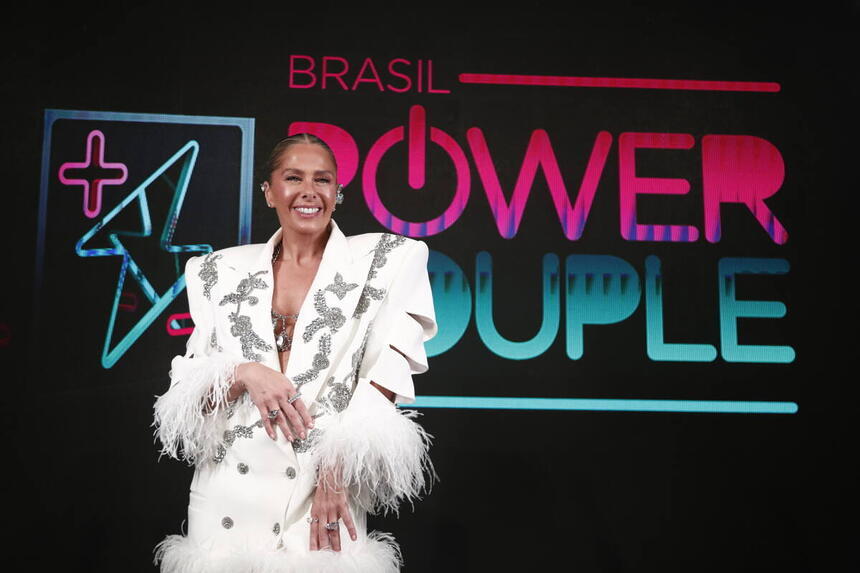 Adriane Galisteu sorrindo no cenário de estreia do Power Couple Brasil 6