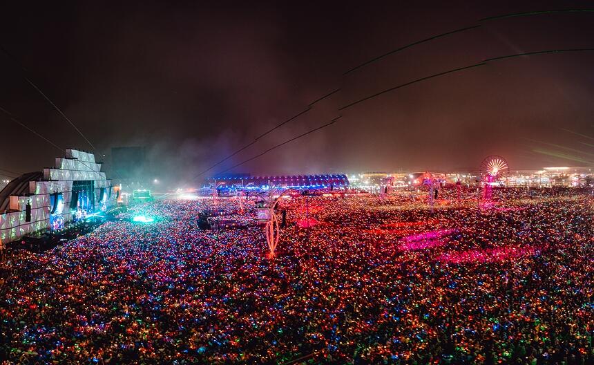 Palco Mundo do Rock in Rio visto de cima pela lente de um drone, cercado por uma multidão com pulseira de LED durante show de Coldplay