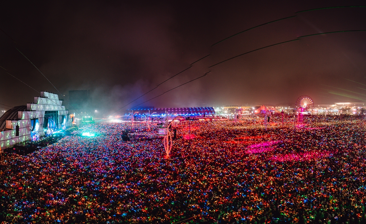 Palco Mundo do Rock in Rio visto de cima pela lente de um drone, cercado por uma multidão com pulseira de LED durante show de Coldplay