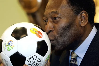 Pelé, de terno, beijando uma bola