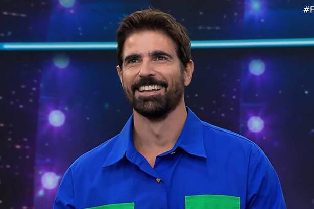 Reynaldo Gianecchini sorrindo, de camisa social azul durante participação no Faustão na Band