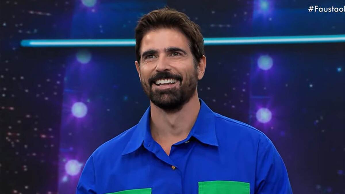 Reynaldo Gianecchini sorrindo, de camisa social azul durante participação no Faustão na Band