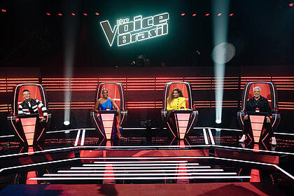 Michel Teló de preto, IZA de azul, Gaby Amarantos de amarelo e Lulu Santos de preto. Técnicos sentados nas cadeiras no palco do The Voice Brasil 11